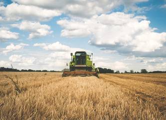 Trecker bei der Weizen Ernte vor Himmel mit Wolken - Symboldbild Ukraine Krieg und Ernährungskrise